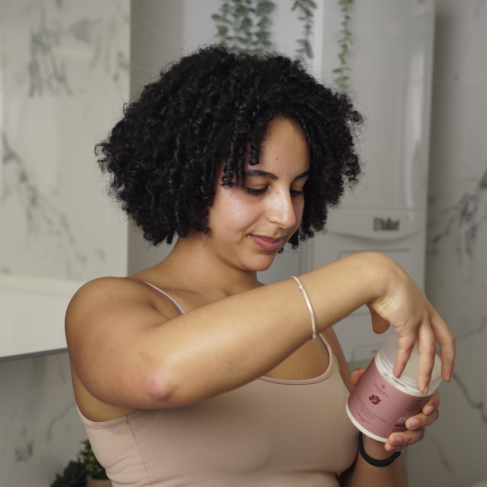 Une femme tenant la Crème capillaire hydratante & fortifiante à l'huile d'hibiscus